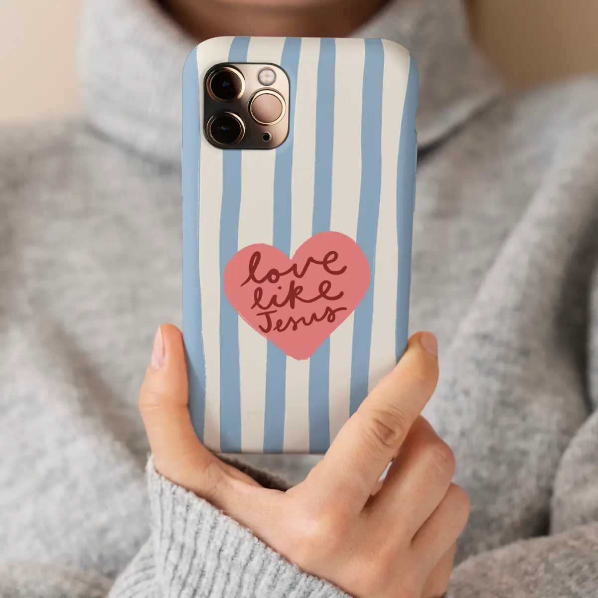 Christelijk hardcase telefoonhoesje Love Like Jesus met lichtblauwe strepen en hart. In hand van mevrouw