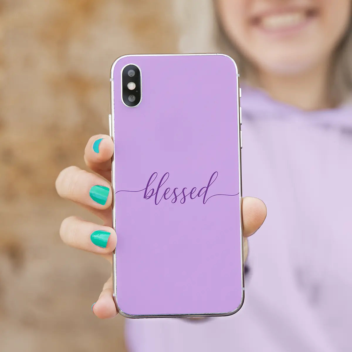Lila softcase telefoonhoesje met de tekst “Blessed” – christelijk design dat herinnert aan Gods zegen. Telefoonhoesje in de hand van een mevrouw
