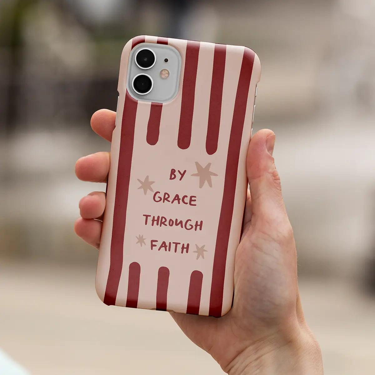 Christelijk softcase telefoonhoesje met de tekst By Grace Through Faith op rood gestreepte achtergrond in hand