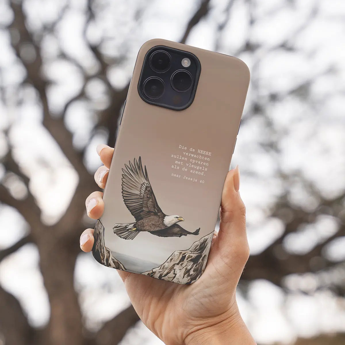 Christelijk softcase telefoonhoesje van Art by Claudia met een arend vliegend tussen bergen en de tekst uit Jesaja 40 in de hand tussen de bomen.