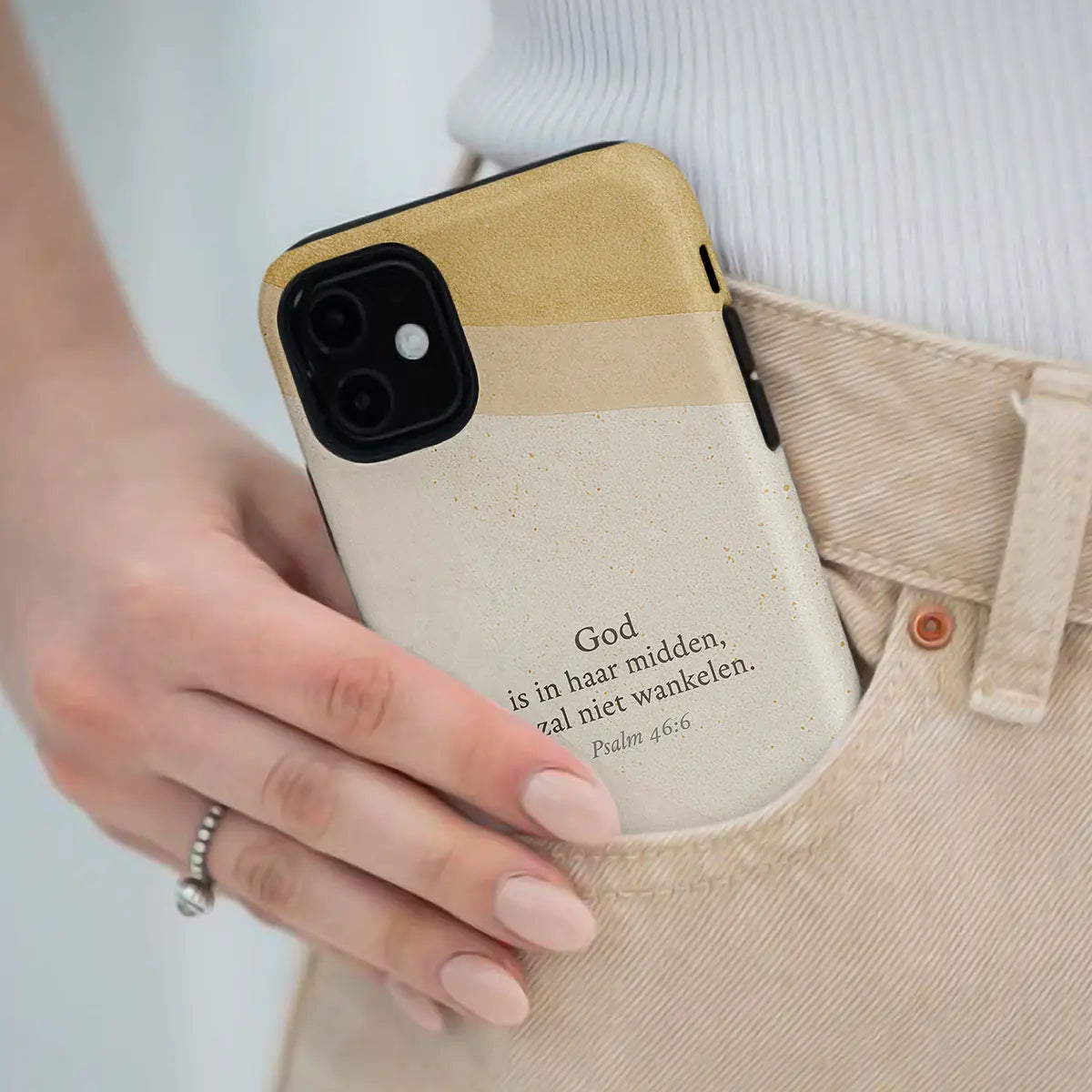 Vrouw houdt een christelijk telefoonhoesje met Psalm 46:6 in haar hand, rustig en minimalistisch ontwerp in aardetinten.