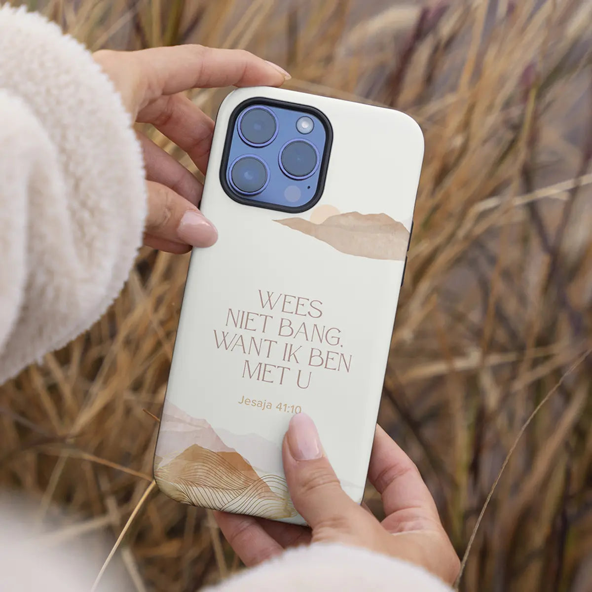 Vrouw houdt het Wees niet bang telefoonhoesje vast met riet op de achtergrond – duurzaam christelijk eco-hoesje geïnspireerd door Jesaja 41:10.