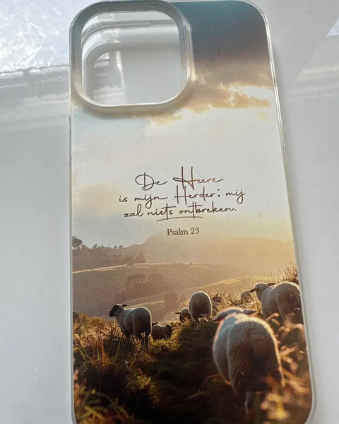 Doorzichtig iPhone-hoesje met de tekst De Heere is mijn Herder, Psalm 23, en schapen in een gouden landschap